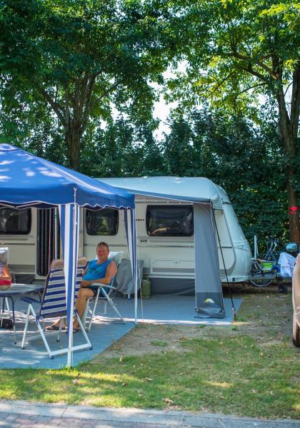 Twee mensen ontspannen voor een caravan met een auto ernaast geparkeerd.